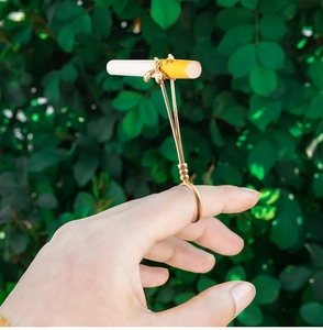 Detailed view of bronze bee cigarette ring holder on finger with garden background