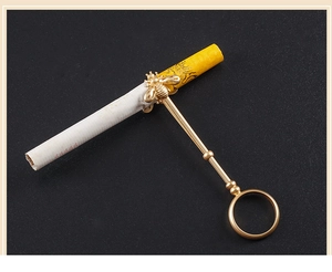 Detail of a golden bee ring holder showing the metal cigarette clip on a dark background