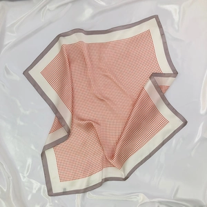 Detail view of the orange houndstooth pattern and rolled edges on a faux silk square scarf