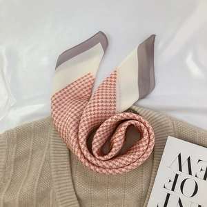 Detail of orange houndstooth silk scarf elegantly styled over a beige knitted sweater