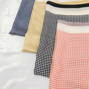 Close-up of four houndstooth silk square scarves in navy, yellow, black and coral colors