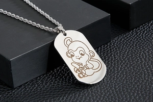 Macro view of a stainless steel dog tag necklace with a carved cartoon monkey pattern