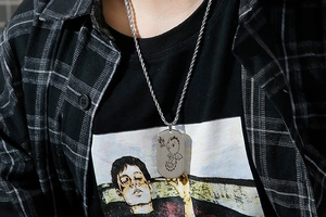 Polished stainless steel dog tag necklace featuring an engraved cartoon dinosaur pendant