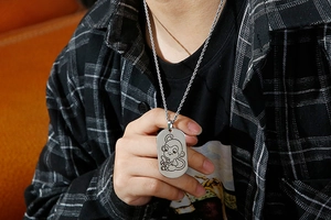 Detail of silver stainless steel dog tag necklace with a monkey engraving worn by a model