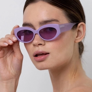 Fashionable lavender cat-eye sunglasses with purple lenses worn by a model in a studio