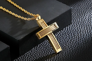 Close-up of gold steel cable cross pendant on black leather with twisted rope chain