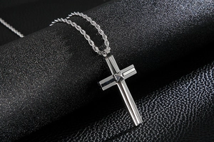 Macro shot of a layered silver cross pendant with a pyramid stud on black leather
