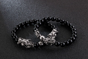 Macro shot of two black beaded bracelets featuring silver metal Pixiu charms for men