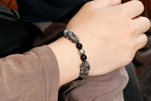 Detailed wrist shot of black obsidian beaded bracelet with silver PiXiu charms