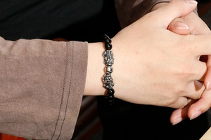 Close-up of beaded bracelet on wrist with black stones and silver Pixiu charms
