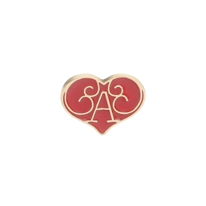 Macro shot of red enamel heart brooch with gold scrollwork and script lettering