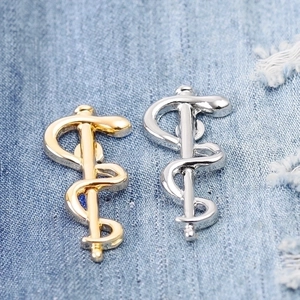 Elegant gold and silver snake medical caduceus brooches on denim fabric background