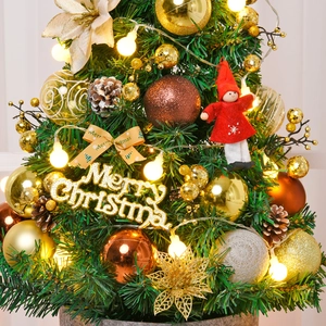 Mini tabletop Christmas tree with warm LED lights, gold ornaments, and Merry Christmas sign