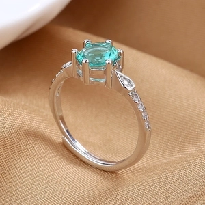 Adjustable silver ring with a six-prong oval sea-blue gemstone and side zircon accents