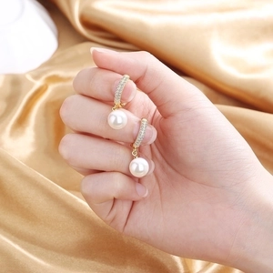 Elegant 18K gold-plated pearl drop earrings with micro-pave crystals on gold satin backdrop