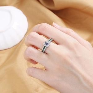 Vintage ring with oval blue gemstone and green side stones on elegant silk fabric
