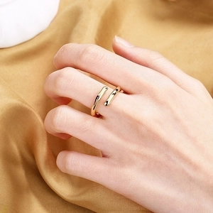 Minimalist gold stream-lined open ring for women on luxurious golden silk background