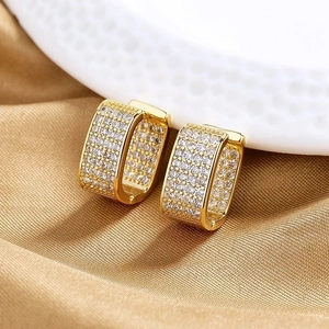 Detailed view of gold square hoop earrings with micro-paved zircons on silk fabric