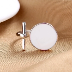 Anello aperto minimalista in argento con finitura bianca su sfondo di tessuto dorato