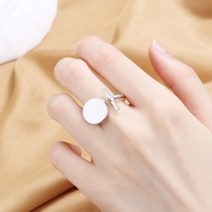 Elegante anello aperto in argento con design bottone in smalto bianco su sfondo di seta
