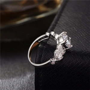 Elegant leaf engagement ring with a round zircon stone on a black leather display