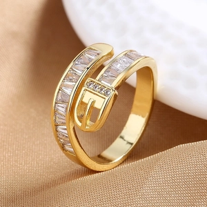Anillo dorado con hebilla de cinturón y circonitas sobre fondo de seda color champán