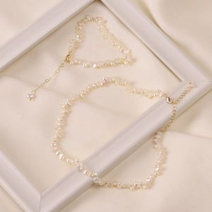 Detail of natural baroque pearl necklace and bracelet set on beige silk background