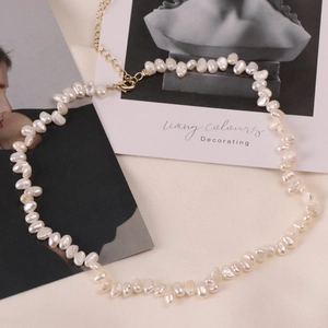 Baroque freshwater pearl necklace with golden clasp displayed on elegant fabric background