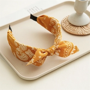 Detail of yellow paisley fabric headband with a stylish top knot on a display tray