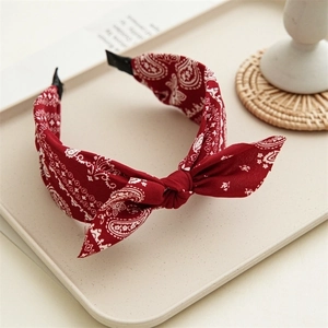 Detail of red paisley knot headband with bow on a tray with decorative props