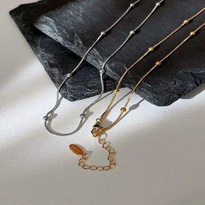Detailed macro view of gold and silver snake bone necklaces on dark stone