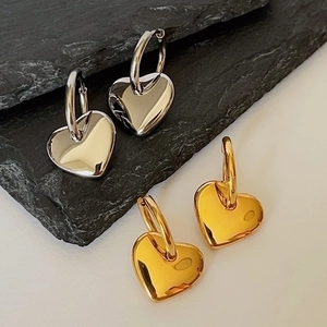 Polished heart drop earrings in gold and silver finish on stone background