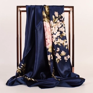 Elegante foulard di seta blu navy con peonie appeso a una cornice di metallo oro rosa