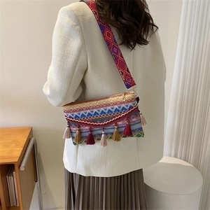 Detail of ethnic woven crossbody bag featuring colorful wavy patterns and long tassels