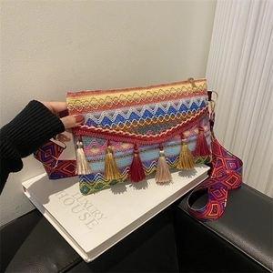 Detail view of colorful woven bohemian envelope bag with tassels and geometric strap