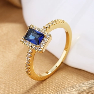 Macro detail of luxury ring with emerald-cut blue gemstone and pavé halo setting