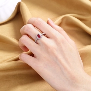 Luxurious silver ring with a large rectangular red gemstone and pavé diamonds on hand