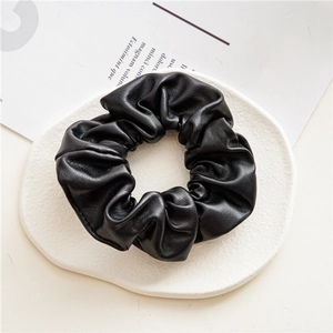 Detail view of a black PU leather scrunchie placed on a white decorative tray