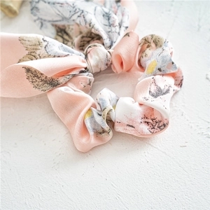 Elegant floral satin hair scrunchie with bow tie detail in soft pink and blue tones