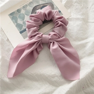 Close-up of pink bow scrunchie showing fabric texture and long ribbon detail