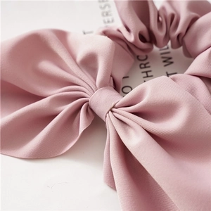 Pink oversized bow scrunchie made of premium smooth fabric with elegant ruffle details