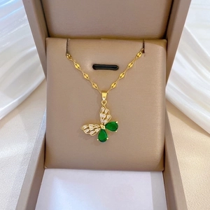 Detailed close-up of gold butterfly necklace with green gems in a gift box