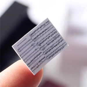 Macro view of a miniature sheet music prop held by fingers for a dollhouse piano
