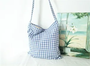Detail of blue and white gingham canvas crossbody bag showing texture and strap