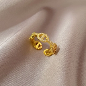 Detail of a gold adjustable chain ring with zircon stones on champagne silk fabric