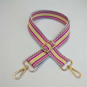 Macro shot of light blue woven bag strap with colorful geometric patterns and gold metal buckles