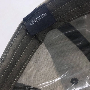 Détail des coutures internes et de l'étiquette 100% coton sur la casquette de camouflage