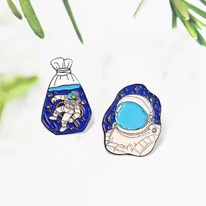 Fashionable astronaut enamel pins set showing a spaceman in a water bag and helmet close-up