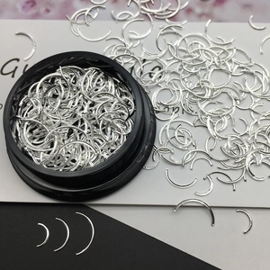 Silver crescent metal nail charms in a black round case for professional manicure art decor