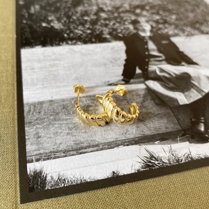 Macro detail of gold textured gear earrings on a vintage photograph background